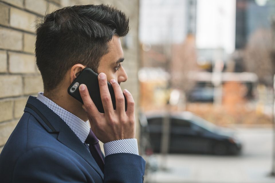 Man in a navy suit and tie taking a phone call