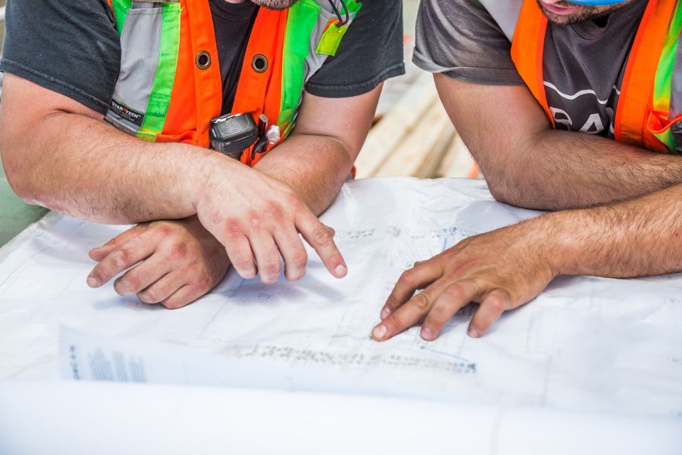 Two site workers reviewing building plans